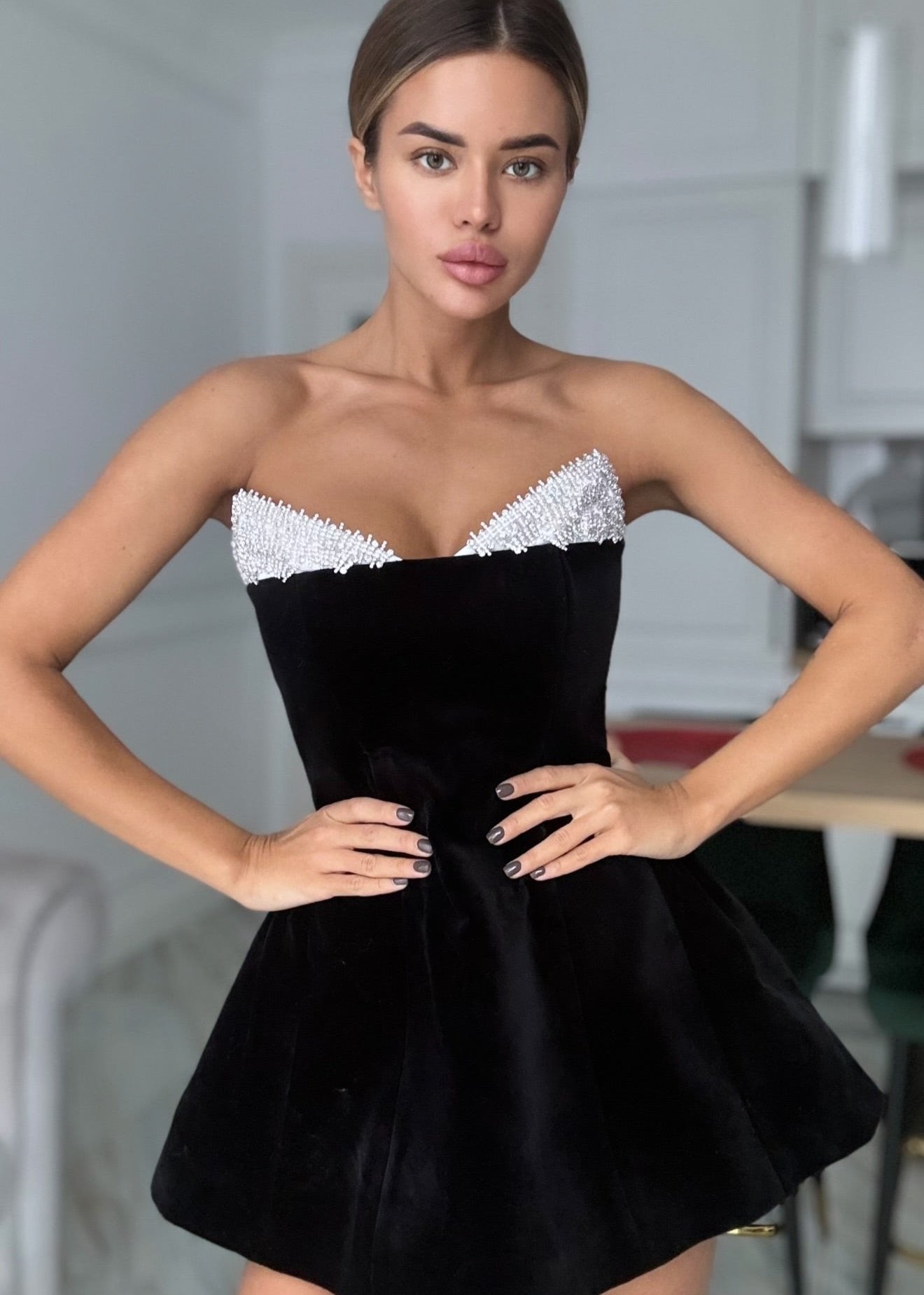 A woman posing in a strapless black velvet dress with rhinestone accents on the neckline.
