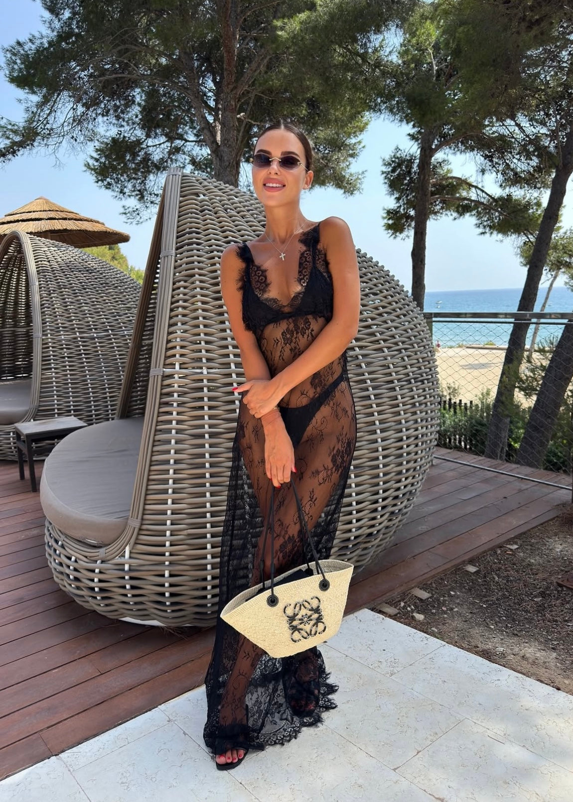 Woman in a black lace dress standing outdoors with a scenic background