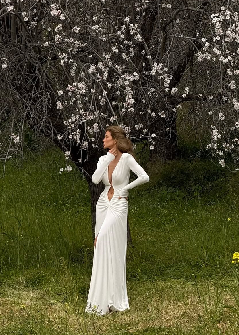 Woman in a white dress standing in front of a flowering tree
