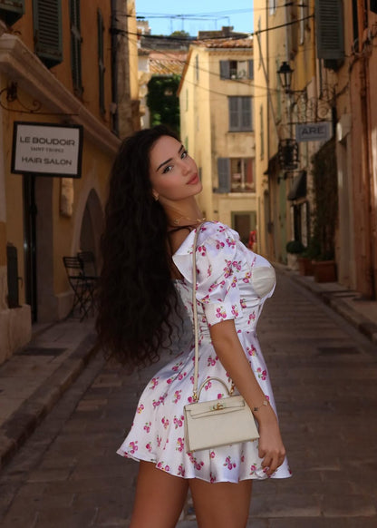 Woman in a floral dress standing on a street in a European town.