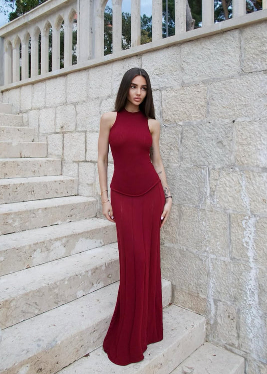 Woman in a burgundy dress standing on stone steps with a stone wall background