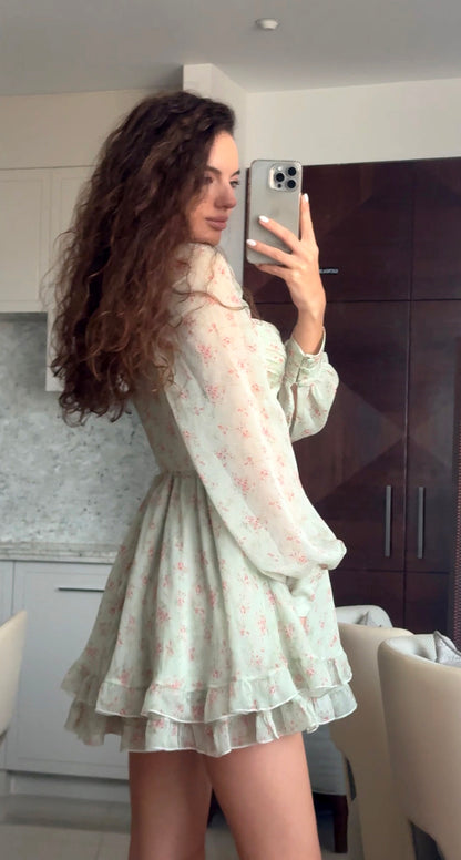 Woman taking a mirror selfie wearing a light-colored dress with floral patterns.