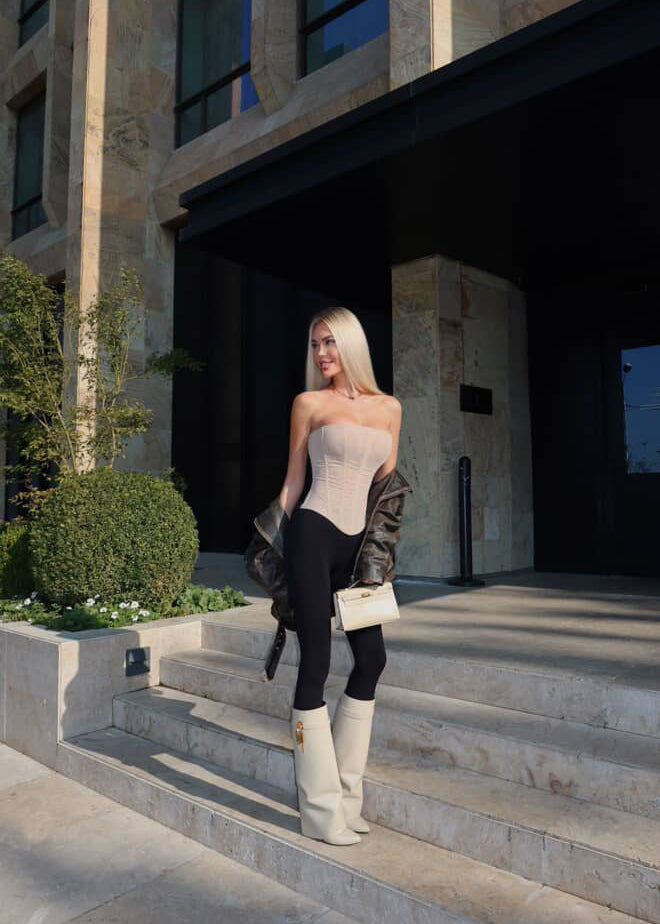 Woman in a stylish outfit standing on steps outside a building