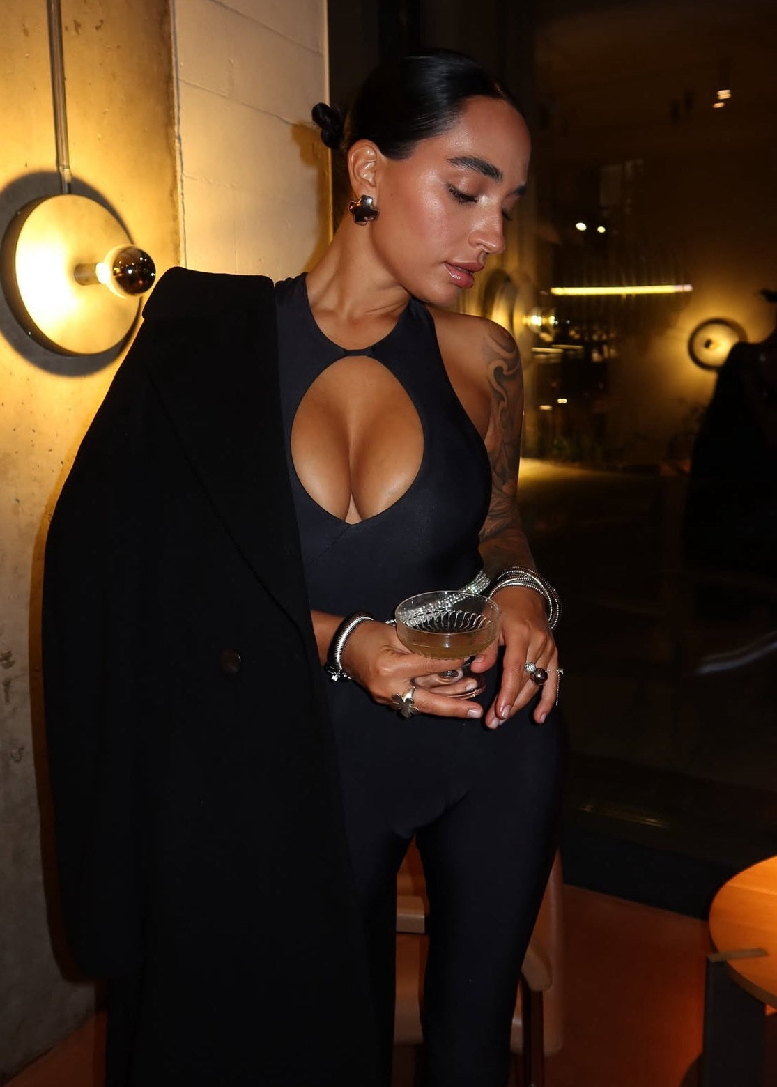 Woman in a black outfit holding an award in a dimly lit room