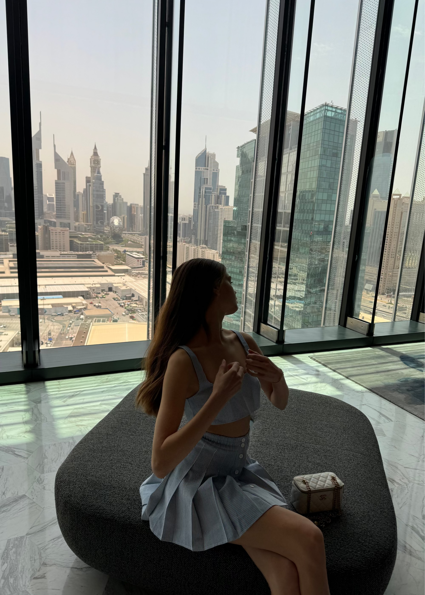 Woman sitting on a ledge with a cityscape view from a high-rise building