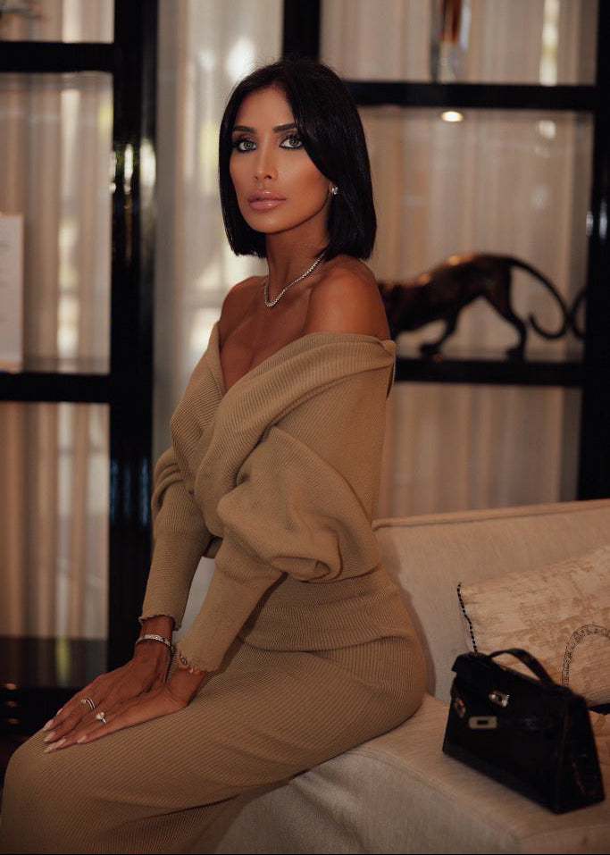 Woman in a beige outfit sitting on a couch with a blurred background