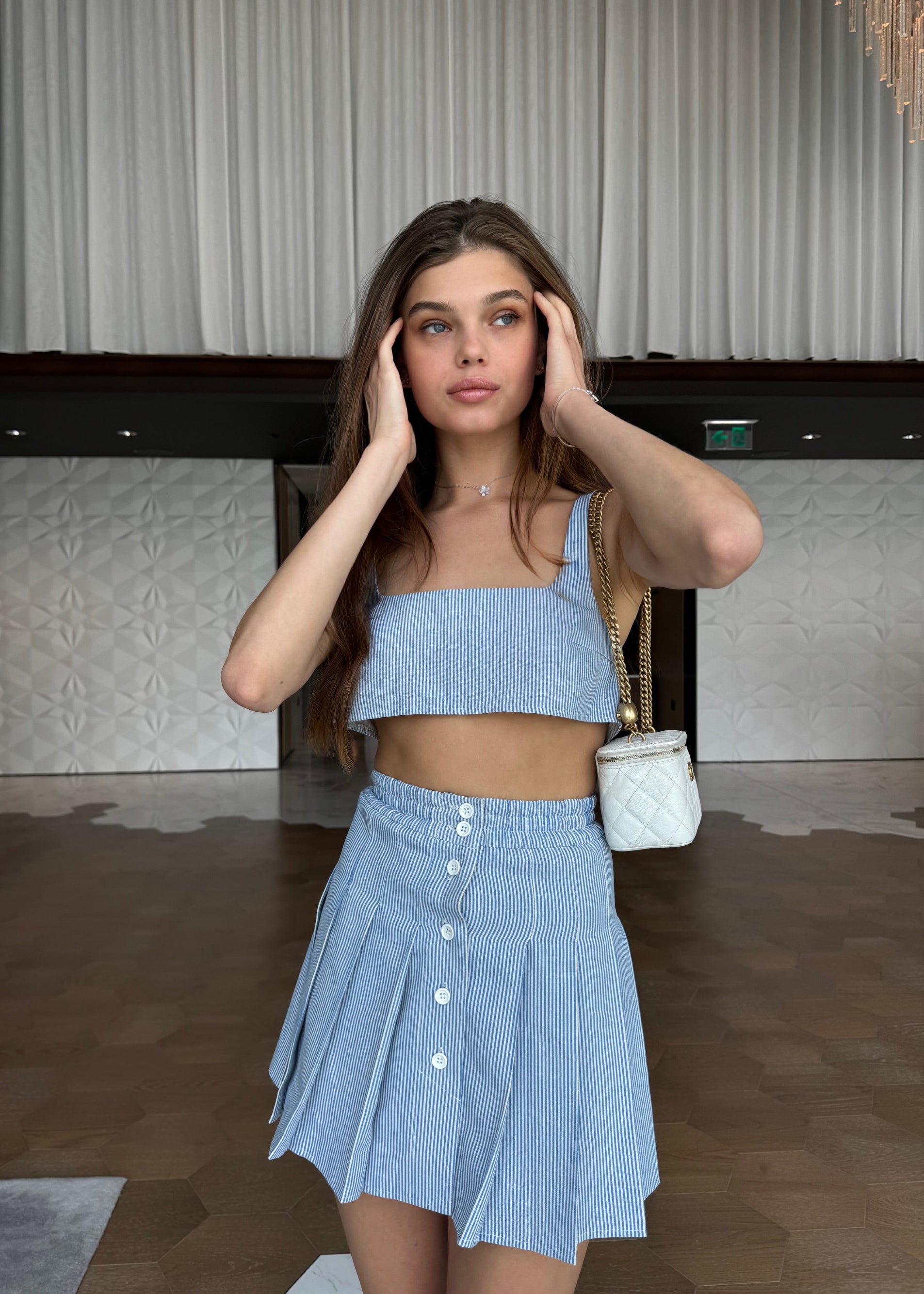 Woman wearing a light blue top and skirt in an indoor setting
