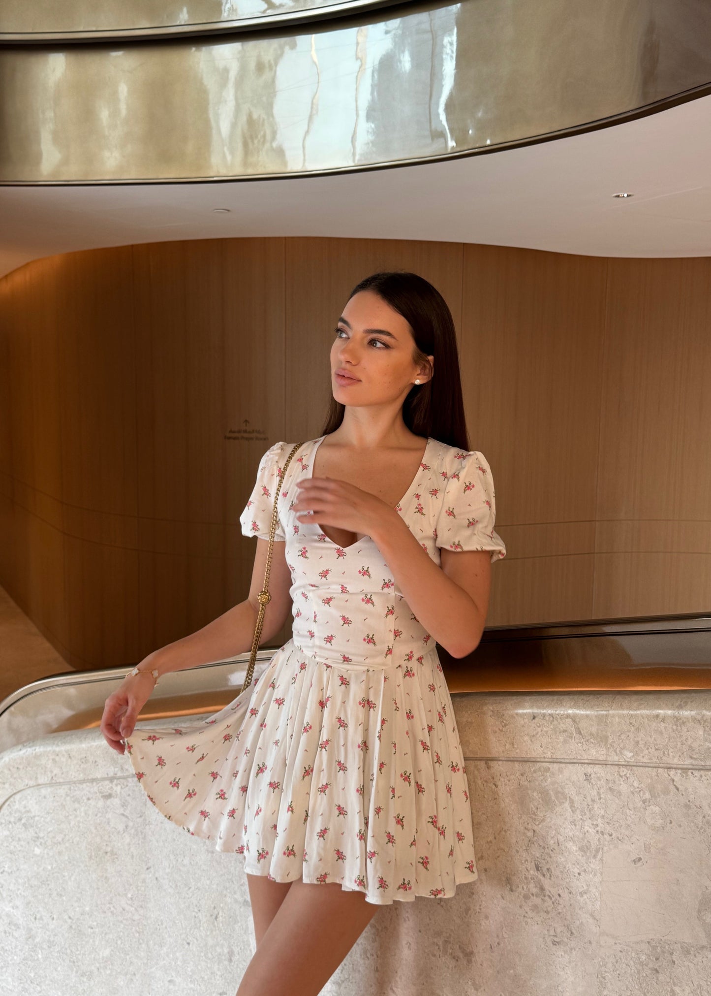 Woman in a floral dress standing in a modern indoor setting