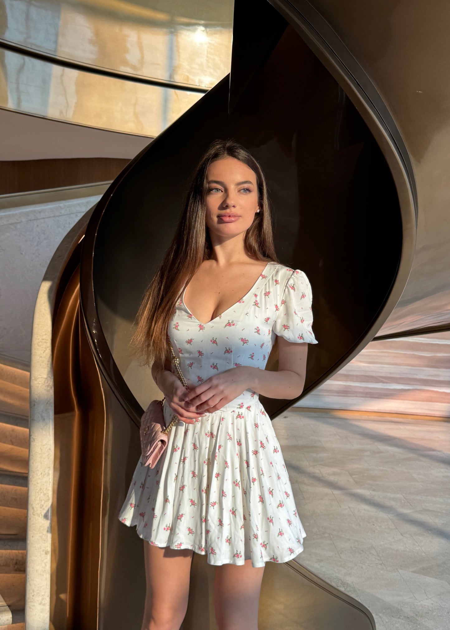 Woman in a white dress standing in front of a modern architectural structure.