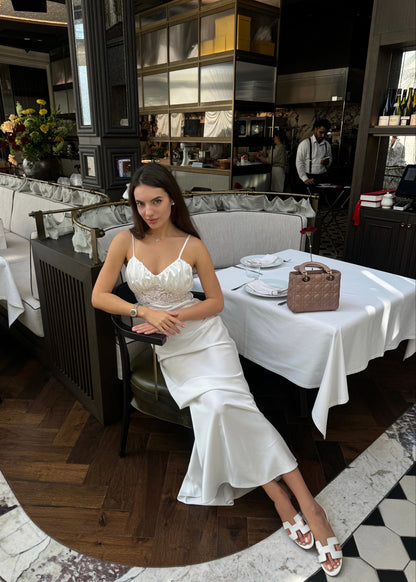 Woman in a white dress sitting at a table in a restaurant.